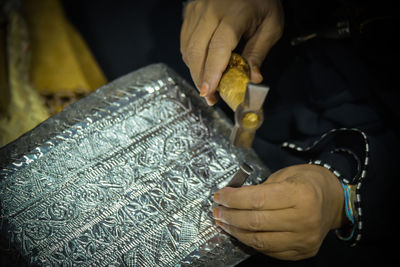 Cropped hands of woman carving metal in workshop