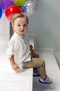 Portrait of a child boy two years old sitting on a wooden floor with balls and number two