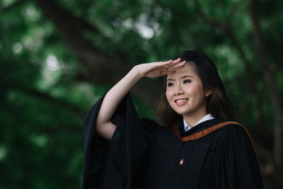 Portrait of young woman standing against trees