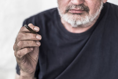Midsection of senior man holding cigar