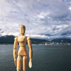 Rear view of statue by sea against sky