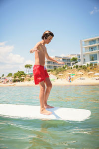 Happy teenage boy having fun on swim board in the sea