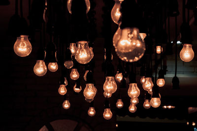 Low angle view of illuminated light bulb hanging on ceiling