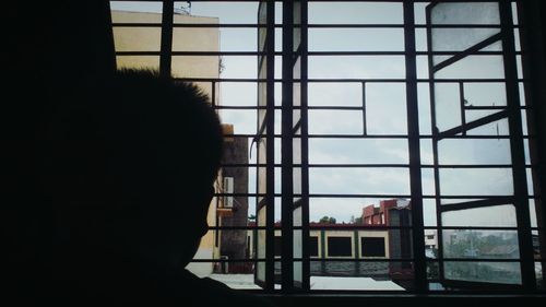 Silhouette man looking through window