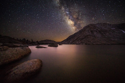 Scenic view of lake and mountains against sky at night