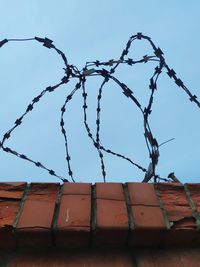 Low angle view of barbed wire fence against sky