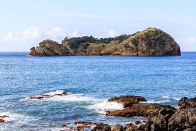 Scenic view of rocks in sea against sky