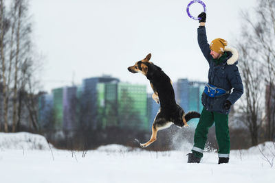 Man playing with dog on snow covered land