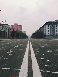 Empty road amidst buildings against sky