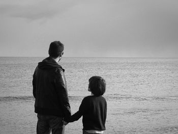 Rear view of father and son standing at beach