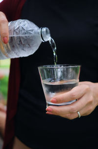 Midsection of person pouring drink in glass