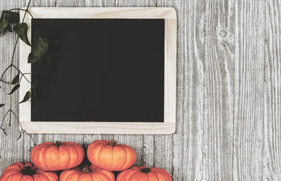 Directly above shot of blackboard and pumpkins on wooden table