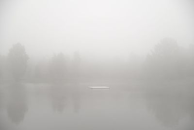 Scenic view of lake against sky during foggy weather