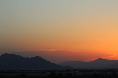 Scenic view of silhouette mountains against orange sky