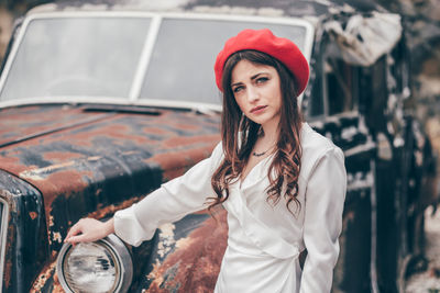 Young woman wearing sunglasses standing against car