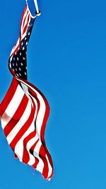 Low angle view of flag against clear blue sky