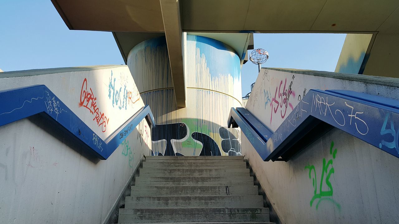 architecture, built structure, building exterior, low angle view, clear sky, building, steps, steps and staircases, residential building, day, wall - building feature, residential structure, city, sunlight, graffiti, art, staircase, blue, outdoors, text