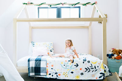 Wide portrait of a toddler girl smiling on her modern bed