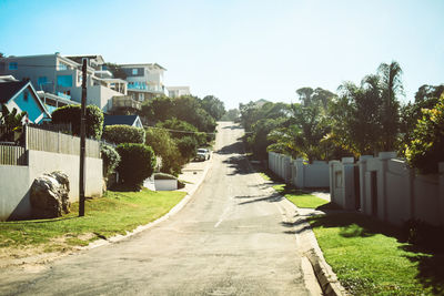 Footpath amidst buildings against clear sky