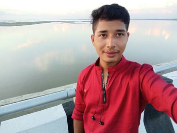 Portrait of young man standing against lake