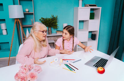 Mother and girl using smart phone on table