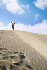 Low angle view of senior man standing on sand dune against sky