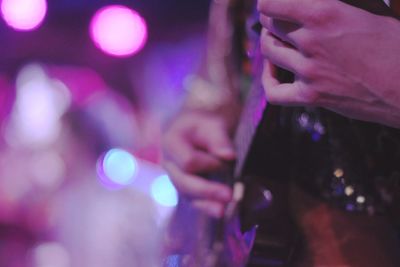 Midsection of guitarist performing at illuminated music concert