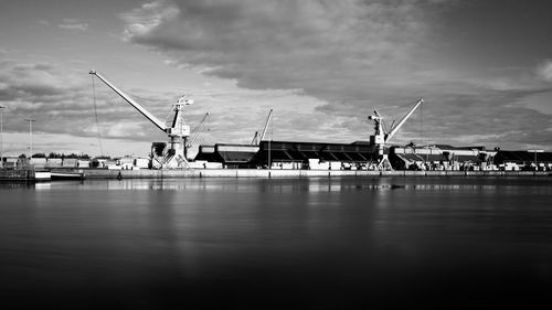 Cranes at harbor against sky