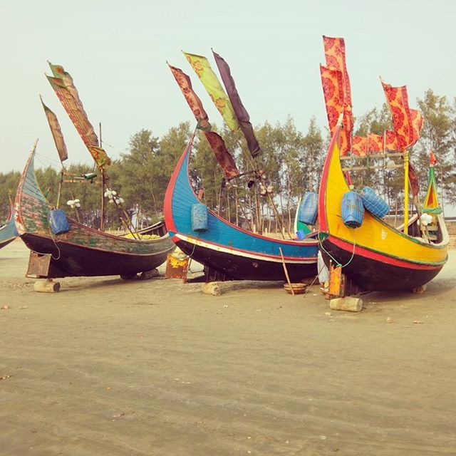 nautical vessel, boat, moored, transportation, mode of transport, beach, sand, sea, water, clear sky, day, blue, rope, group of objects, no people, travel, outdoors, sky, fishing net, beach umbrella