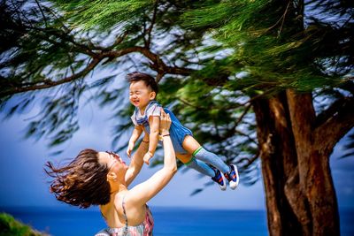 Full length of mother and daughter on tree against plants