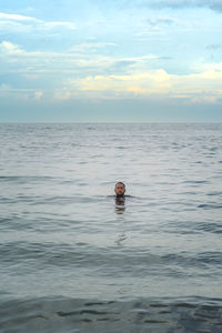 Man swimming in sea against sky