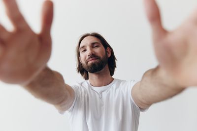 Young man with arms raised standing against white background