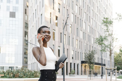 Female freelancer talking on smart phone in city