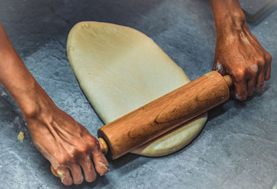 High angle view of man flattening dough on wax paper