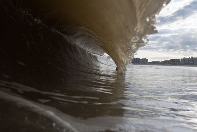 Close-up of water flowing in sea against sky