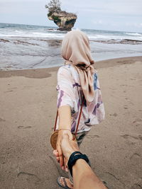 Boyfriend holding hand of girlfriend at beach