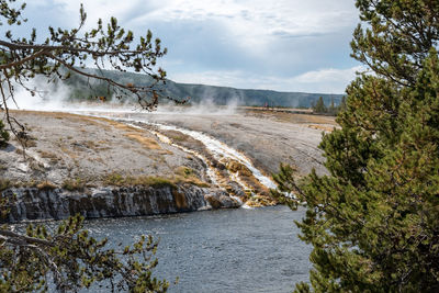 Smoke emitting from hotspring by firehole river in midway geyser basin at park