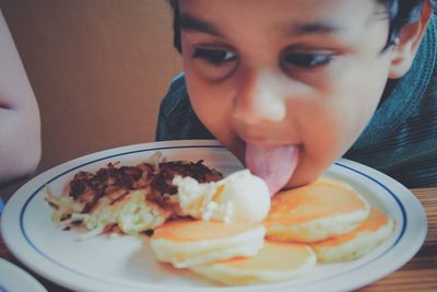 Close-up of cute boy licking food in plate