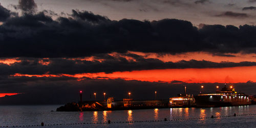 Illuminated ship by sea against sky during sunset