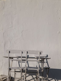 Empty white outdoor chairs and table against whiite wall