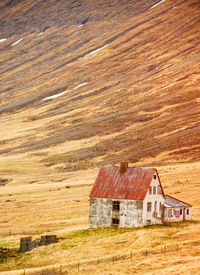 Isolated house in icelandic countryside. steep hills behind.