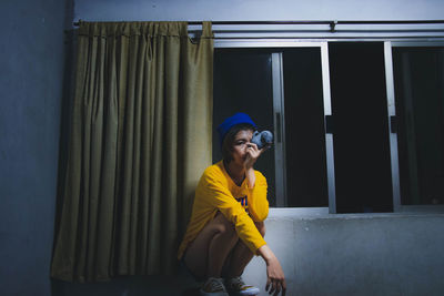 Portrait of young woman with toy crouching at home