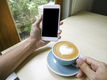 Midsection of woman holding coffee cup on table