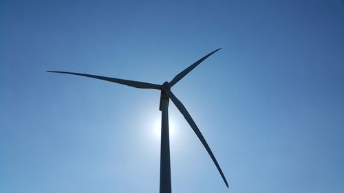 Low angle view of wind turbine against clear blue sky