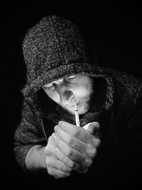 Portrait of man holding cigarette against black background