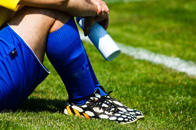 Low section of soccer player sitting on field