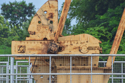 Close-up of rusty machine part by trees against sky