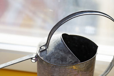 Detail from a metal watering can standing in the window seen from above