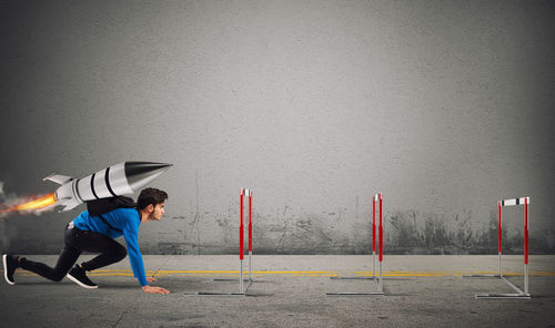 Side view of man standing against wall in city