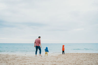 Father and children at the beach on a cloudy and cold day